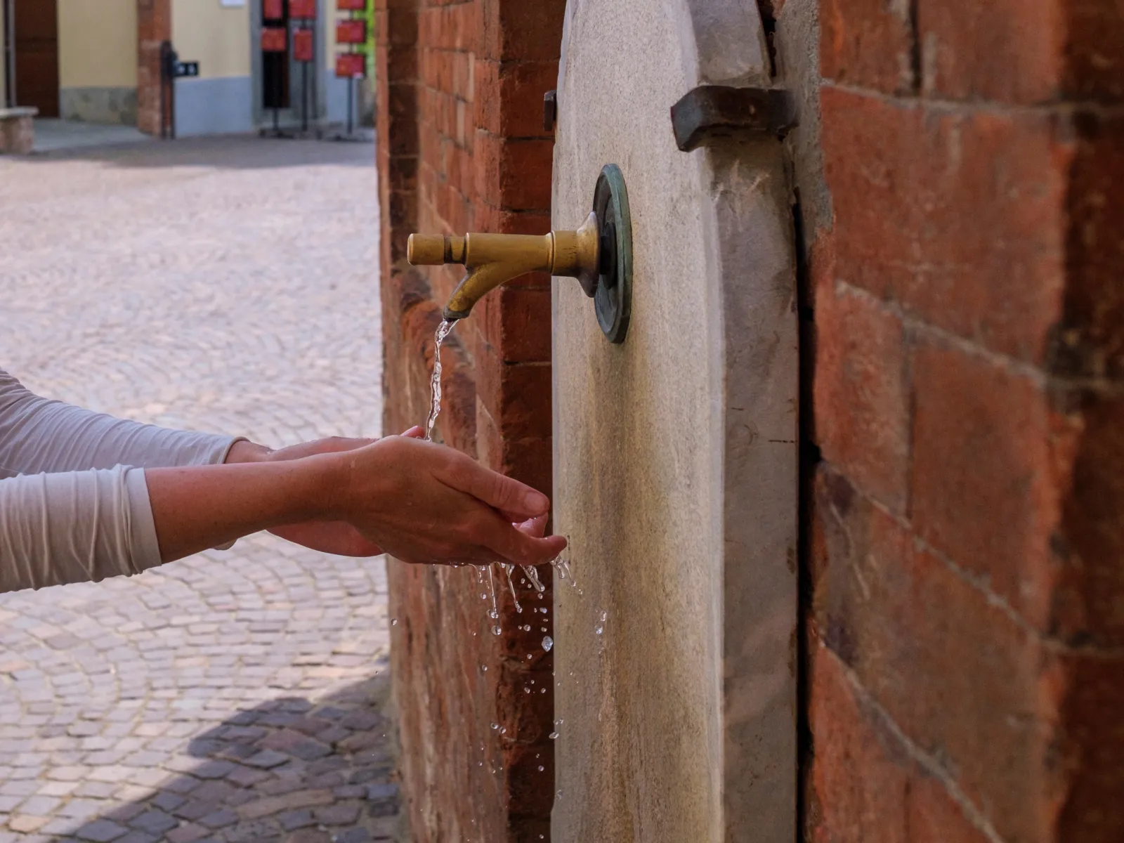 Hände, die Wasser aus einem Wasserspender auffangen