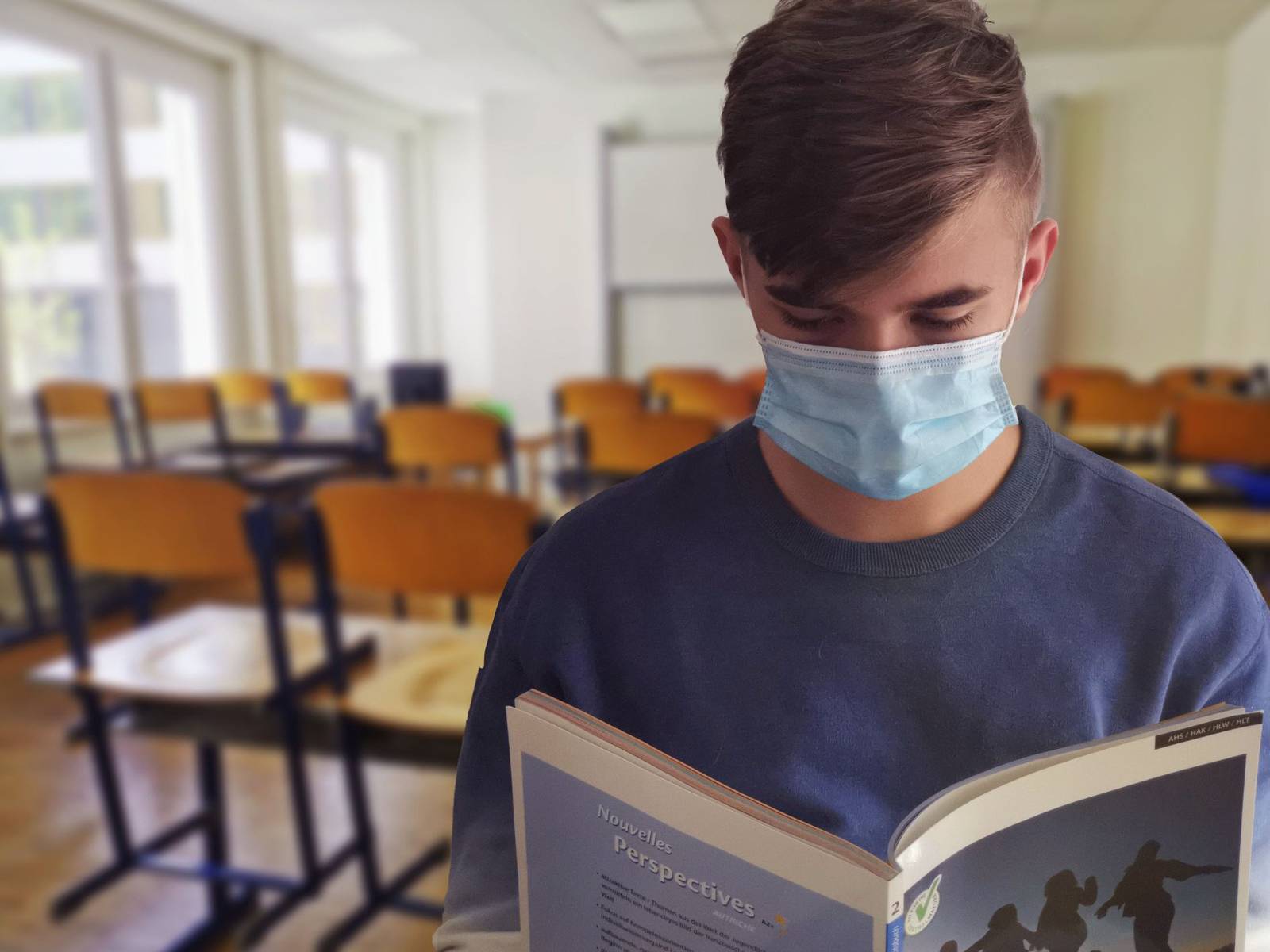 Ein Schüler, der eine OP-Maske trägt und ein Buch liest.