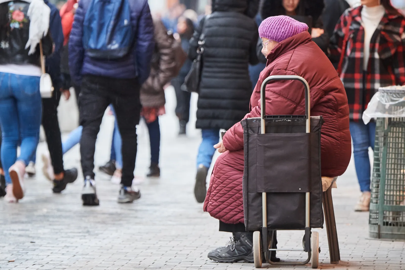 Homeless person begging on a busy shopping street