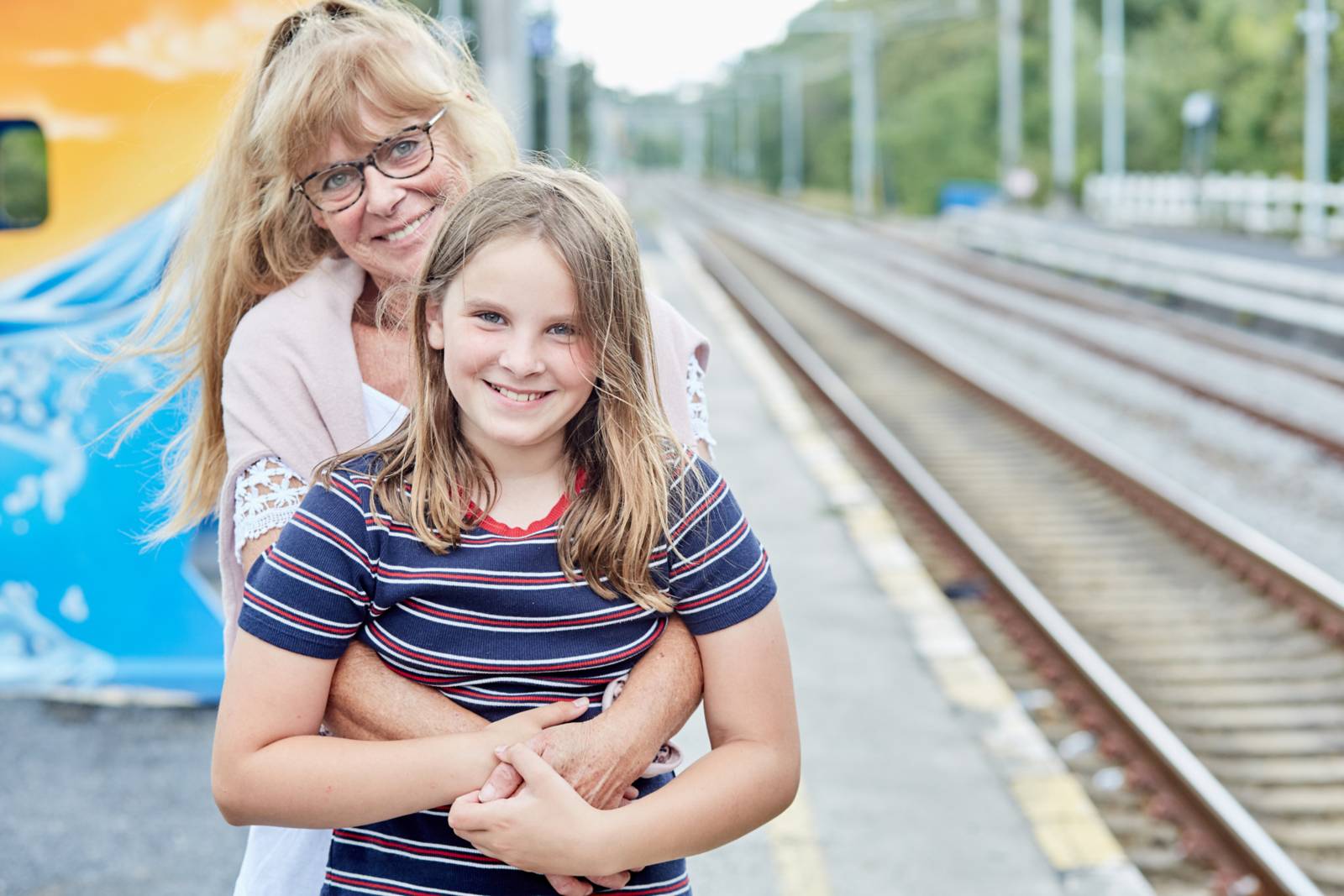 Portrait of a grandmother and her granddaughter next to the train rails