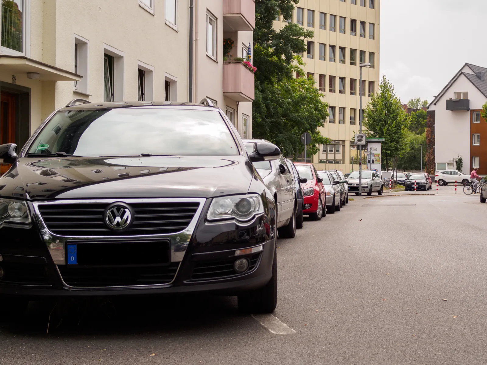 Eine Straße in einer Wohngegend mit parkenden Autos am Rand.