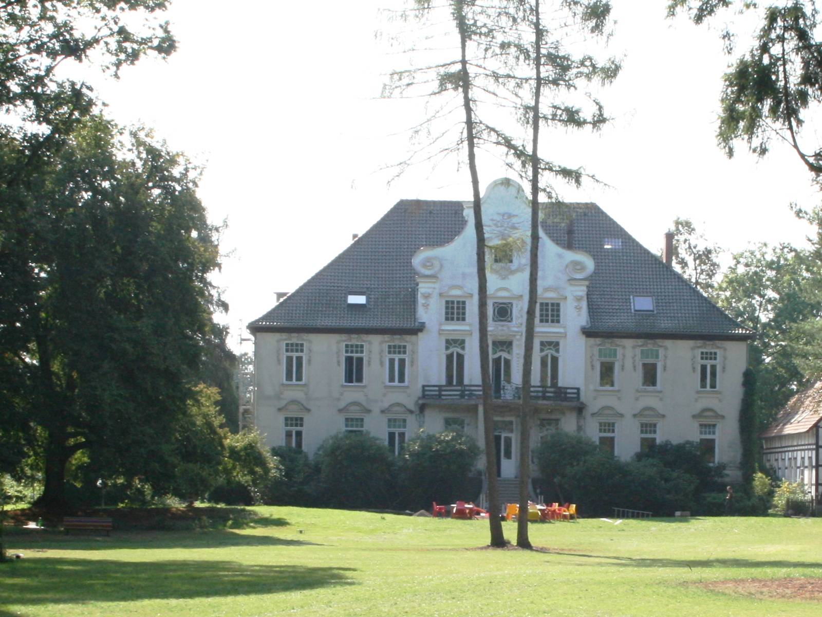 Blick über eine gepflegte Rasenfläche auf das Hauptgebäude des KulturGutes Poggenhagen.