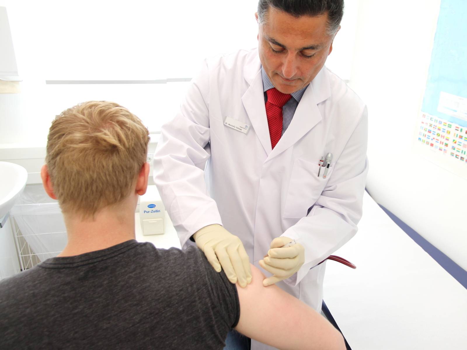 Ein Arzt gibt einem jungen Mann eine Spritze in den Oberarm