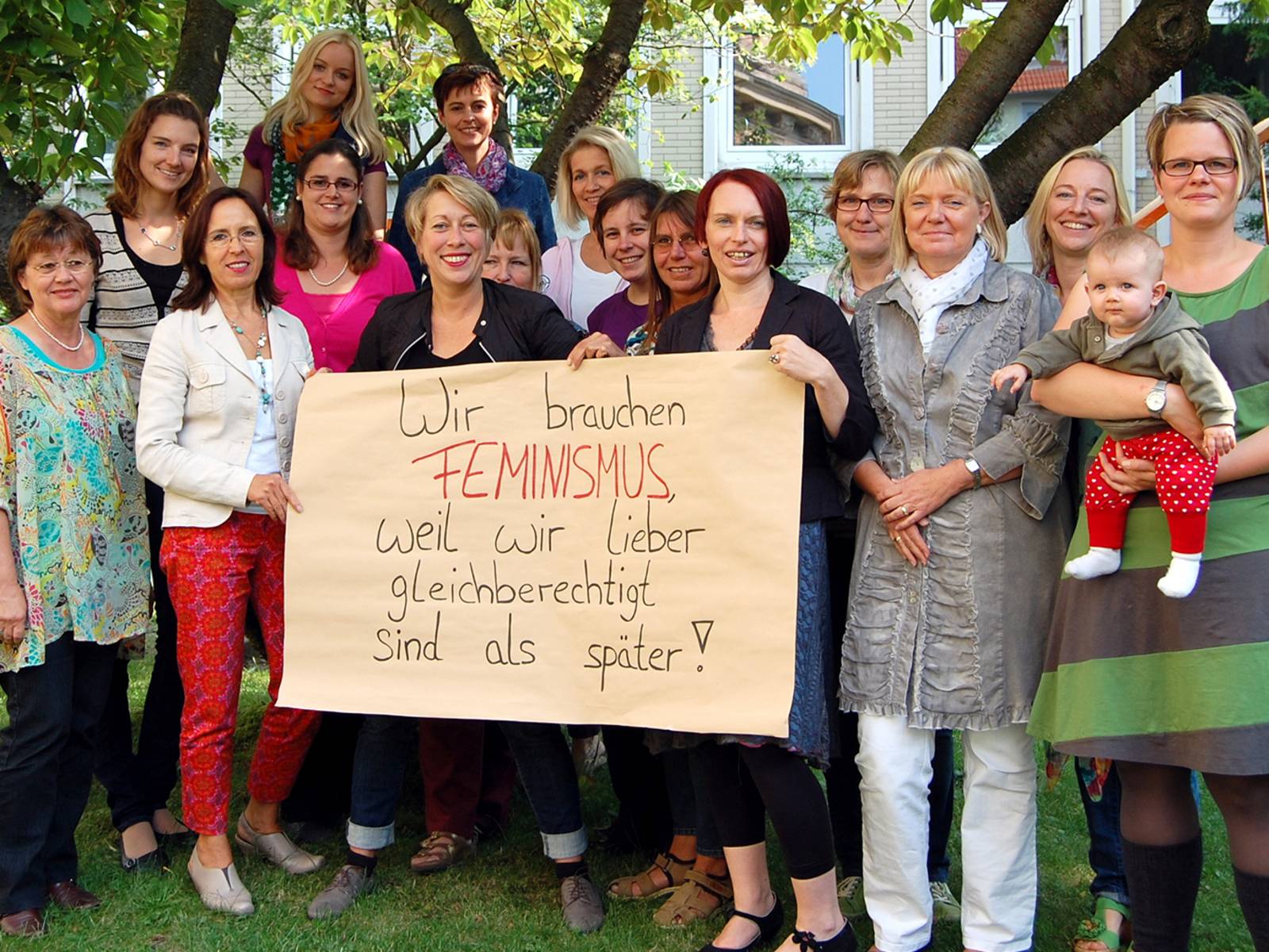 Viele Frauen stehen für ein Gruppenbild zusammen. Drei Frauen halten ein Plakat.