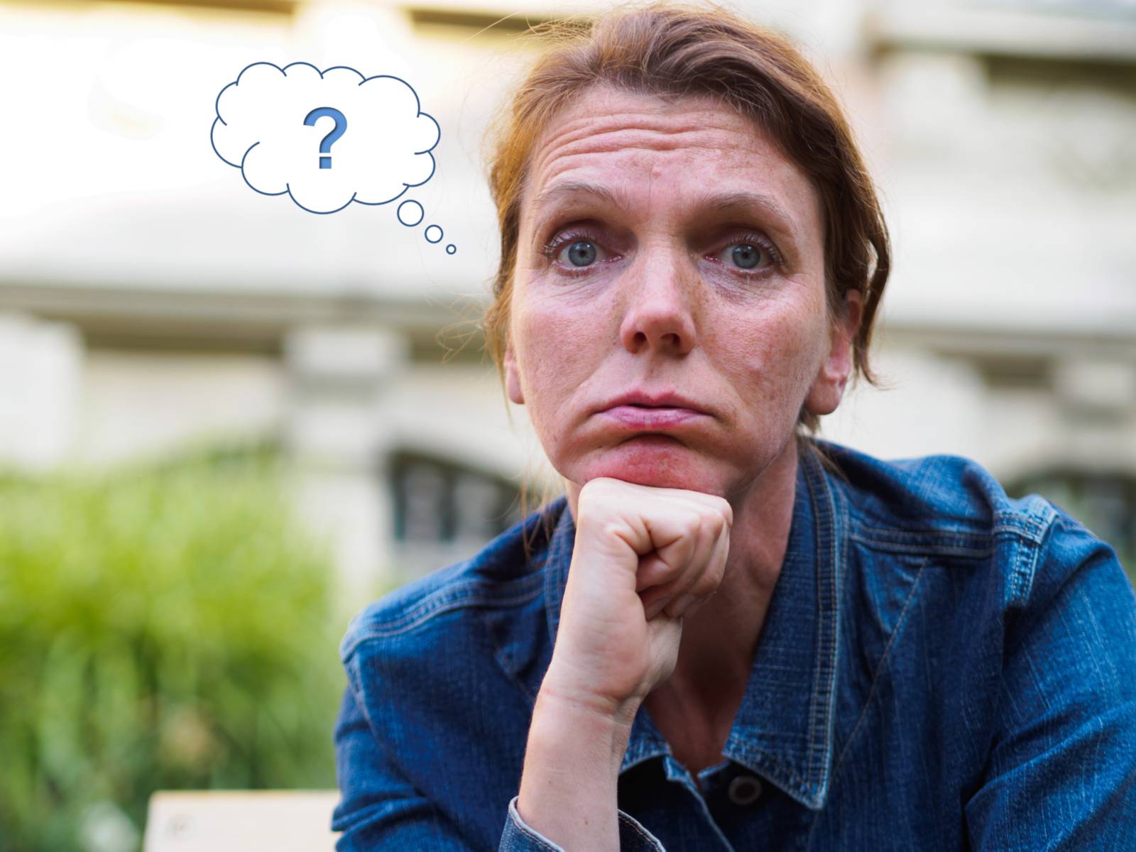 Eine Frau mit fragendem Gesichtsausdruck. Links neben dem Kopf ist eine Grafik die eine Gedankenblase mit Fragezeichen hat.
