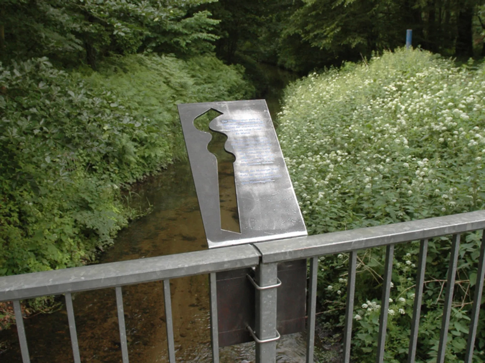 Metalltafel an einem Brückengeländer