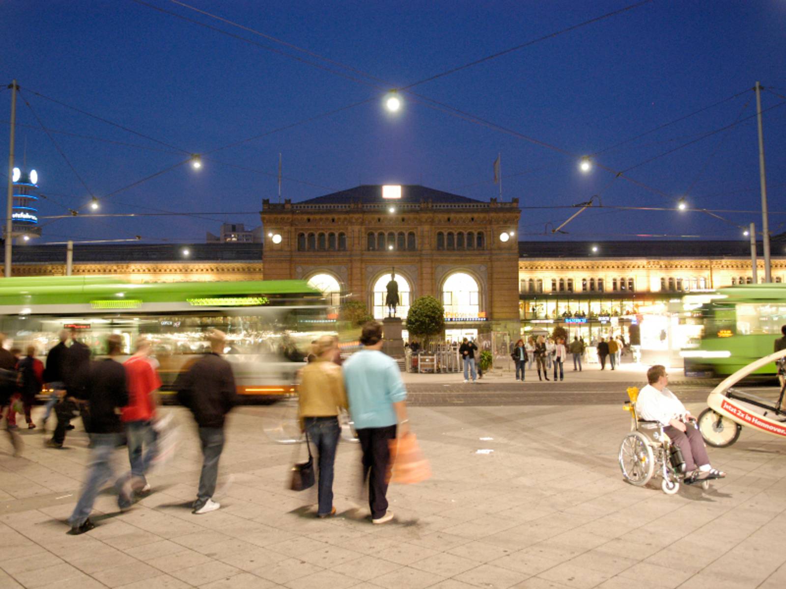 Menschen und Öffis vor dem Hauptbahnhof Hannover (bei Nacht).