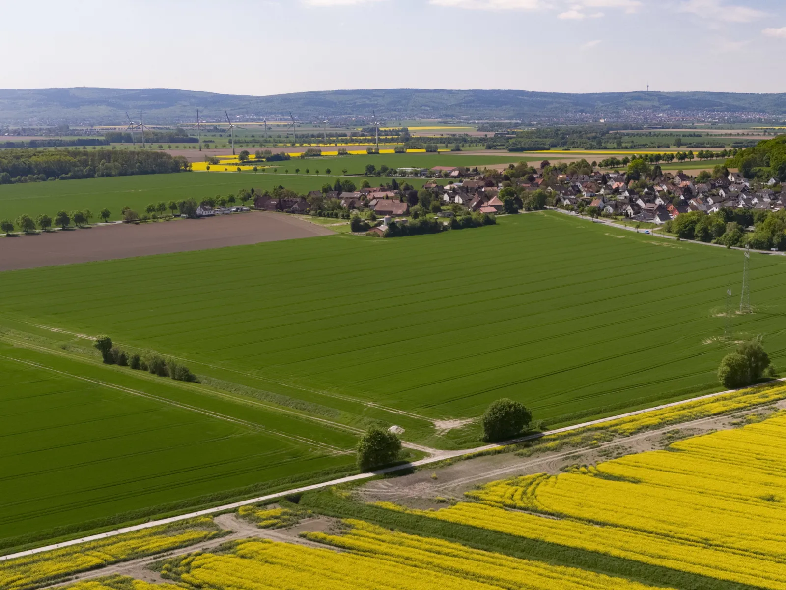 Luftbild der Ortschaft Göxe, im Hintergrund Windkraftanlagen und der Deister