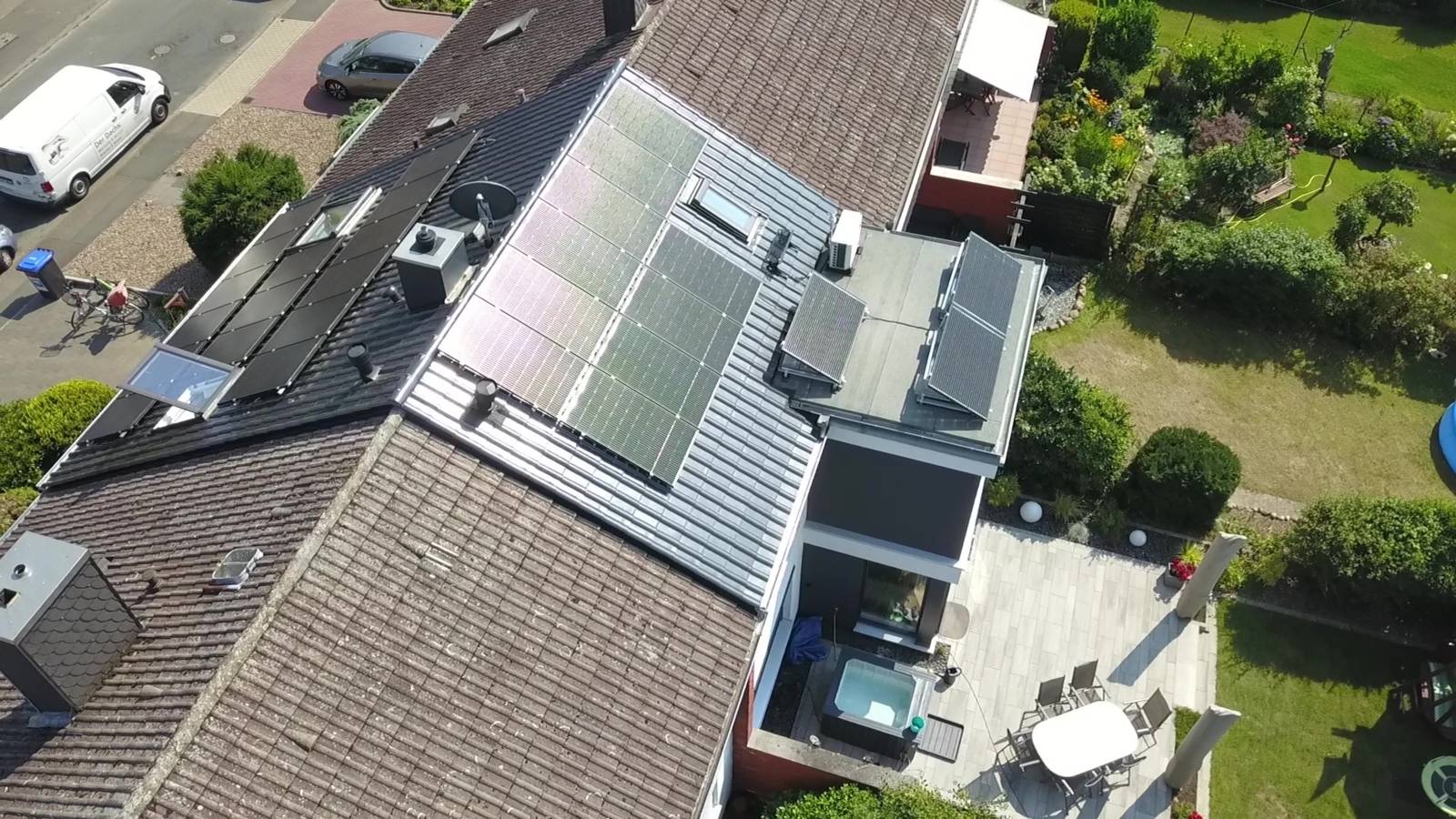 Luftaufnahme von mehreren Hausdächern, auf einem ist eine Photovoltaik-Anlage zu sehen