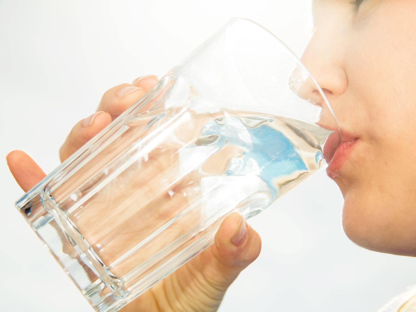 Eine Frau, die Wasser aus einem großen Glas trinkt