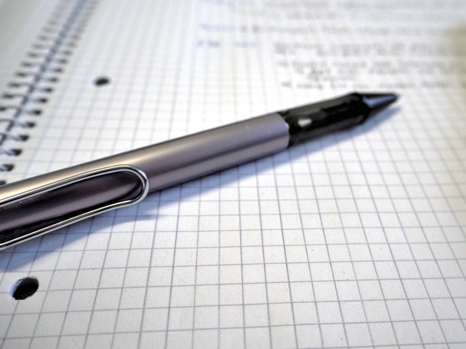 Ein Kugelschreiber liegt auf einem Schreibblock mit kariertem Papier. Handschriftliche Notizen stehen auf dem Papier.