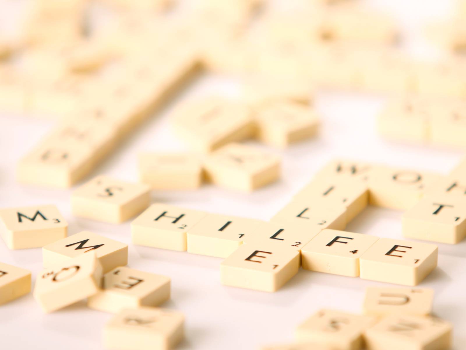 Spielsteine tragen einzelne Buchstaben. Einige liegen durcheinander, andere bilden zum Beispiel Worte "Hilfe" und "Wille".