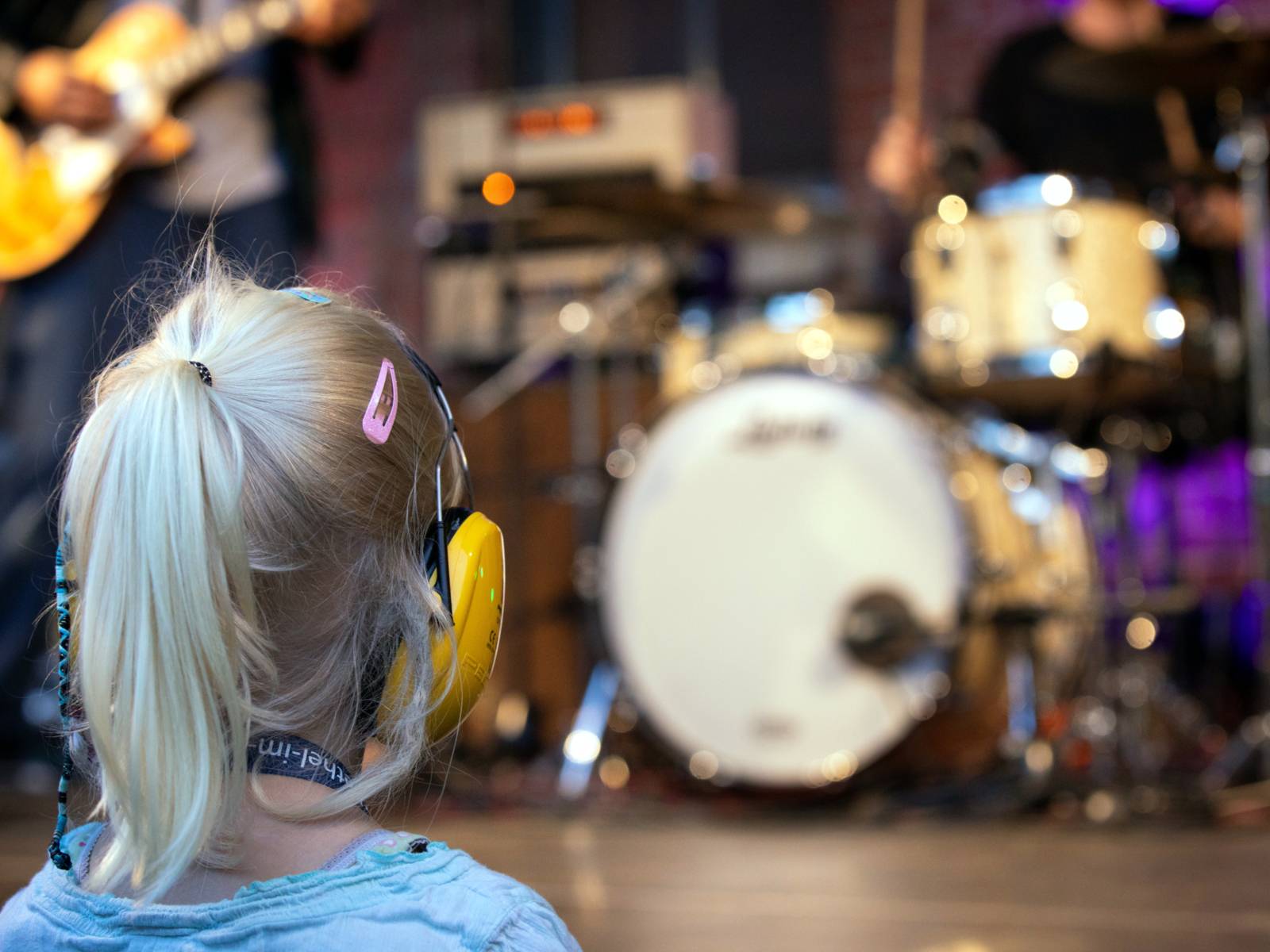 Ein Kind trägt Gehörschutz und schaut sich ein Live-Konzert an.