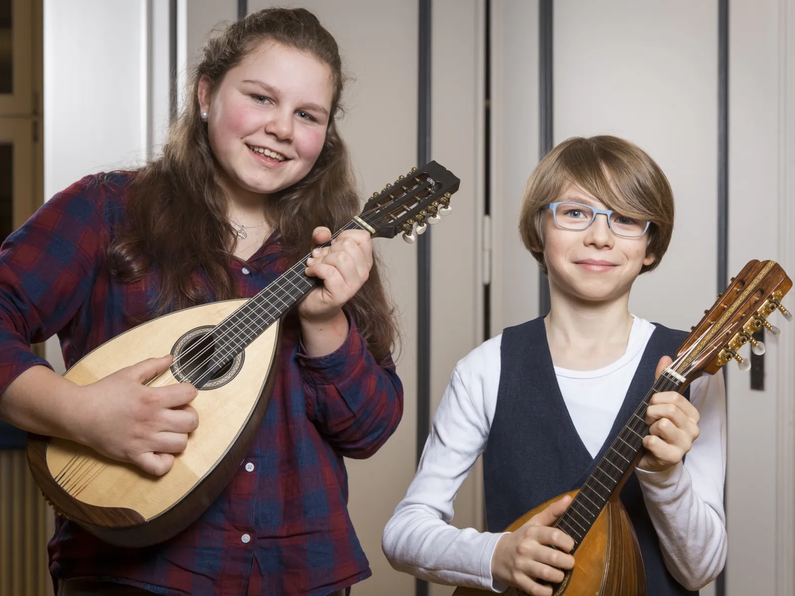 Ein Mädchen mit einer Mandoline, neben einem Jungen mit Mandoline. 