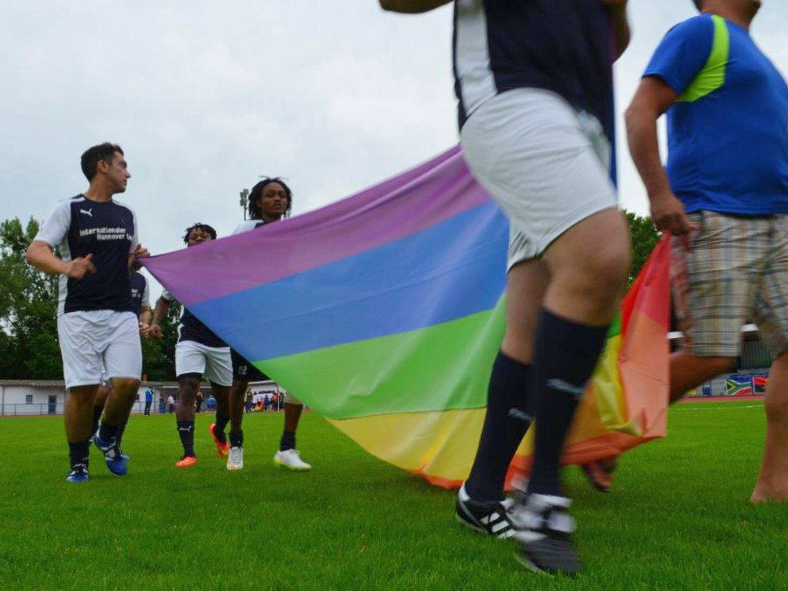 Fünf Personen tragen eine Regenbogenfahne