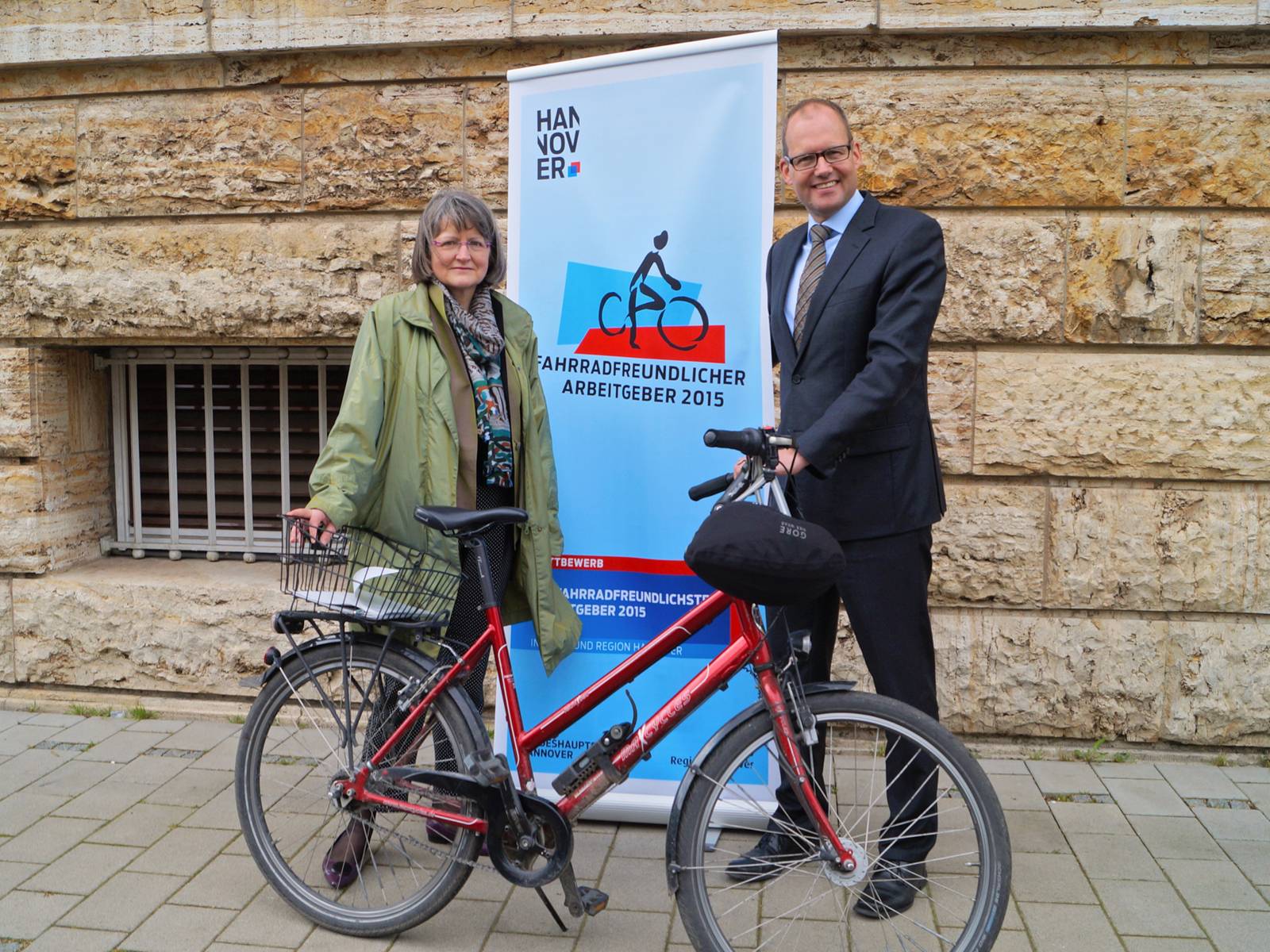Kay de Cassan und Birger Franz mit einem Fahrrad vor einem Roll-Up