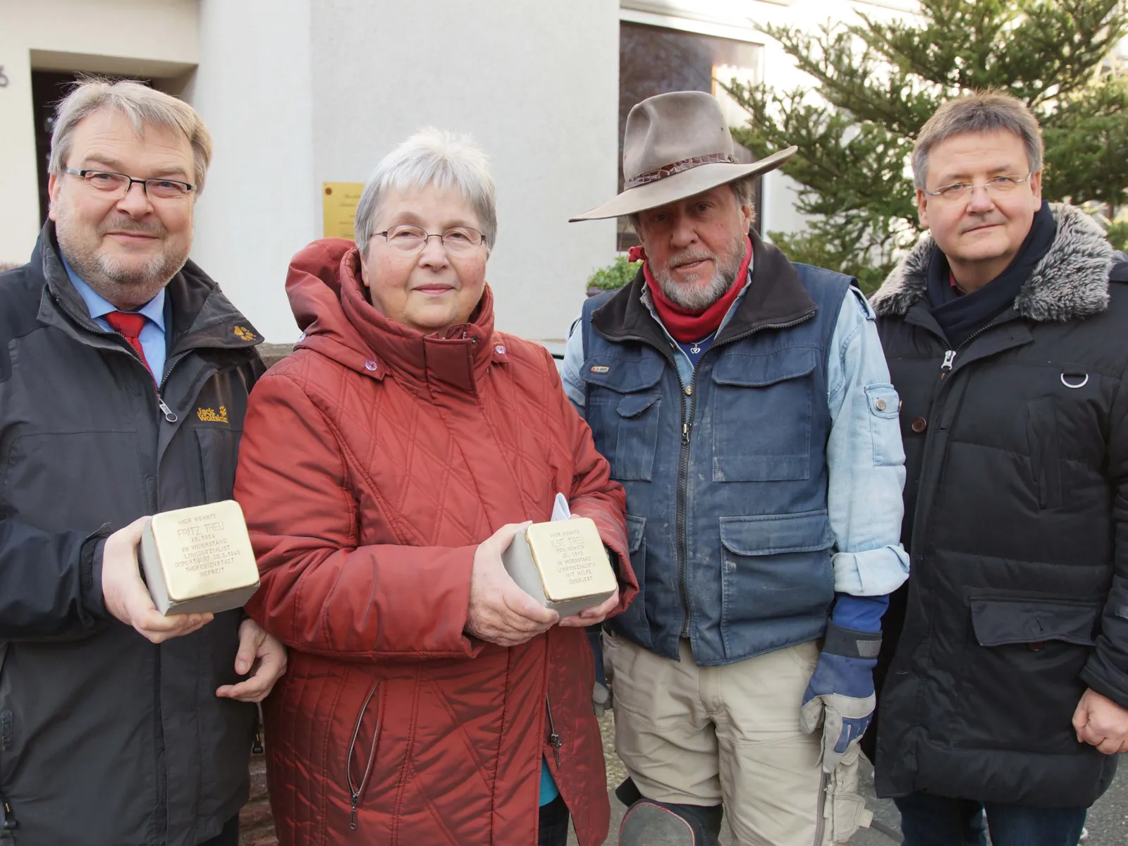 Drei Männer und eine Frau mit zwei Stolpersteinen.
