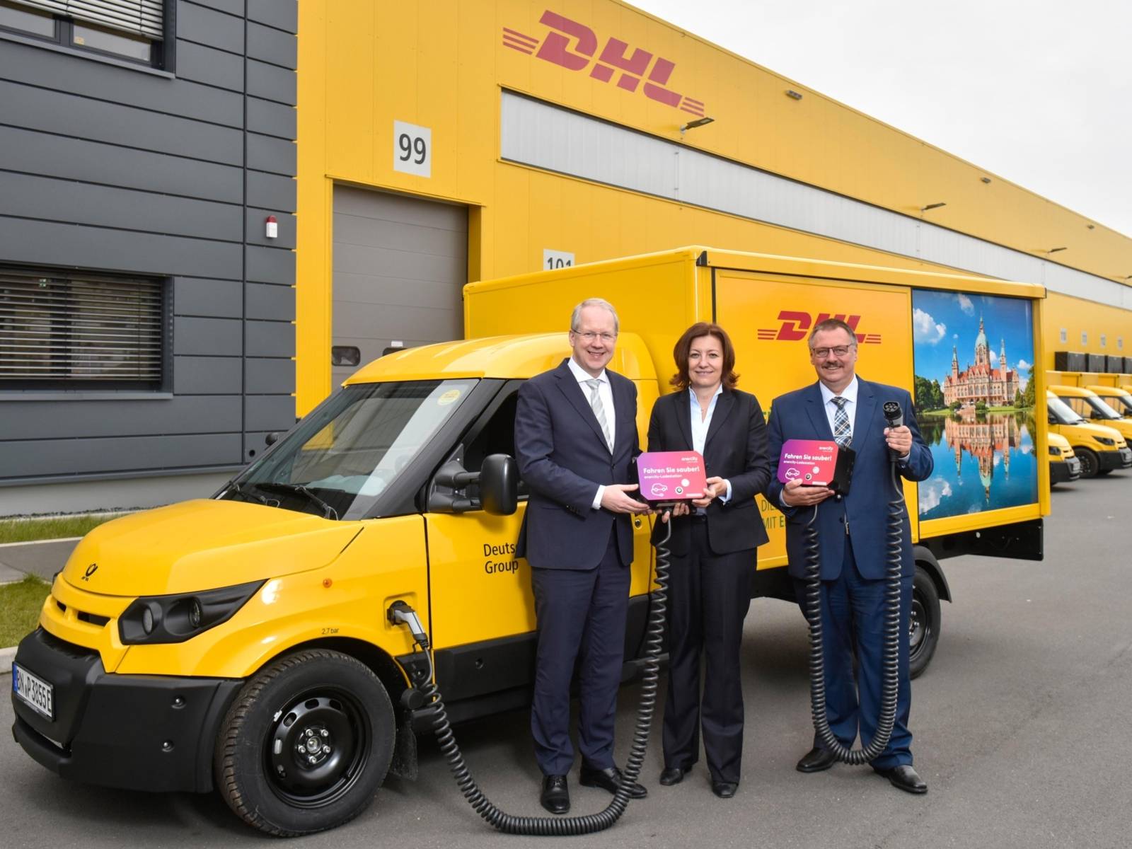 Zwei Männer und eine Frau vor einem Auto. 