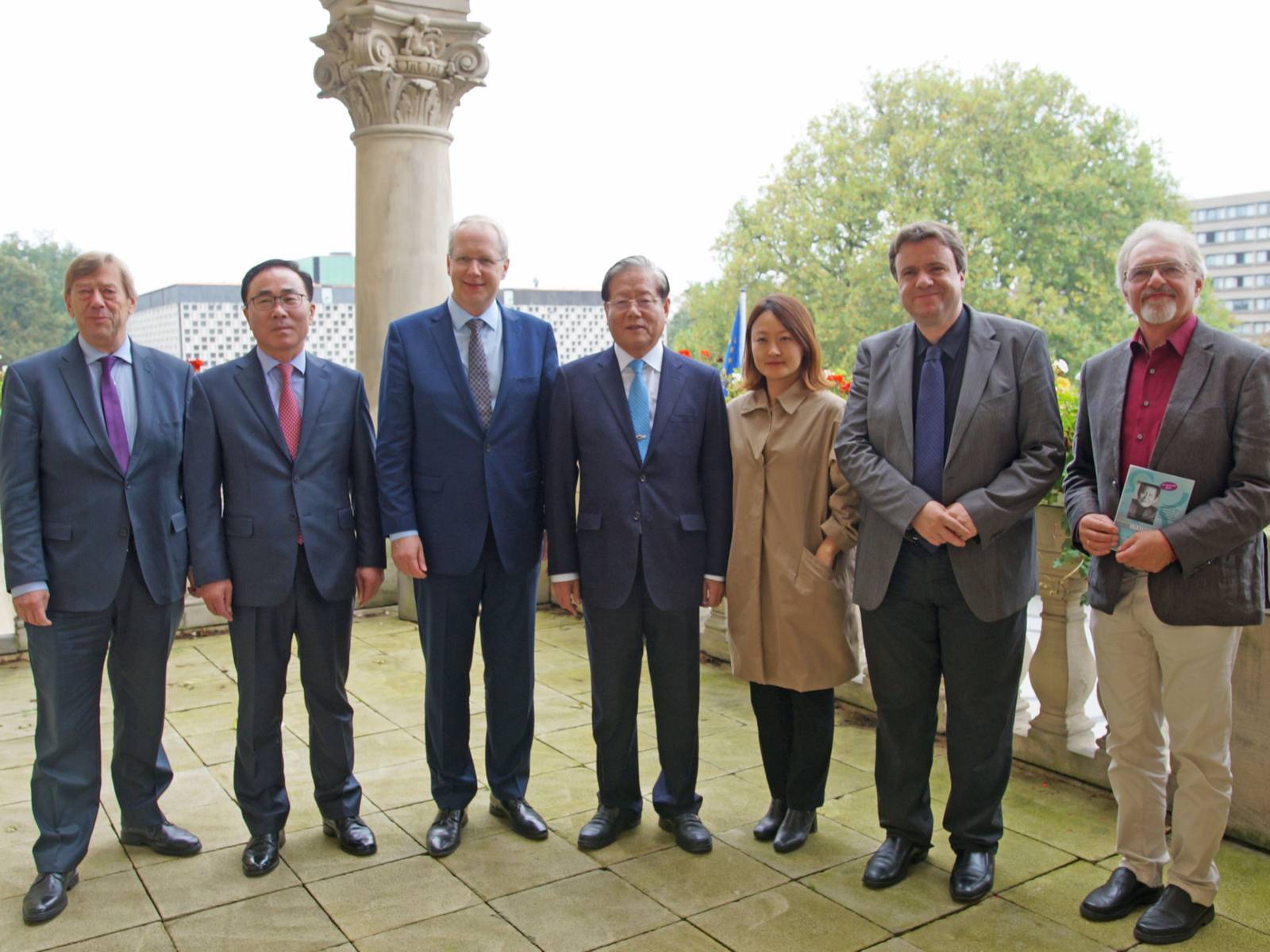 Eine Gruppe Menschen steht nebeneinander. Im Hintergrund befindet sich eine Säule.