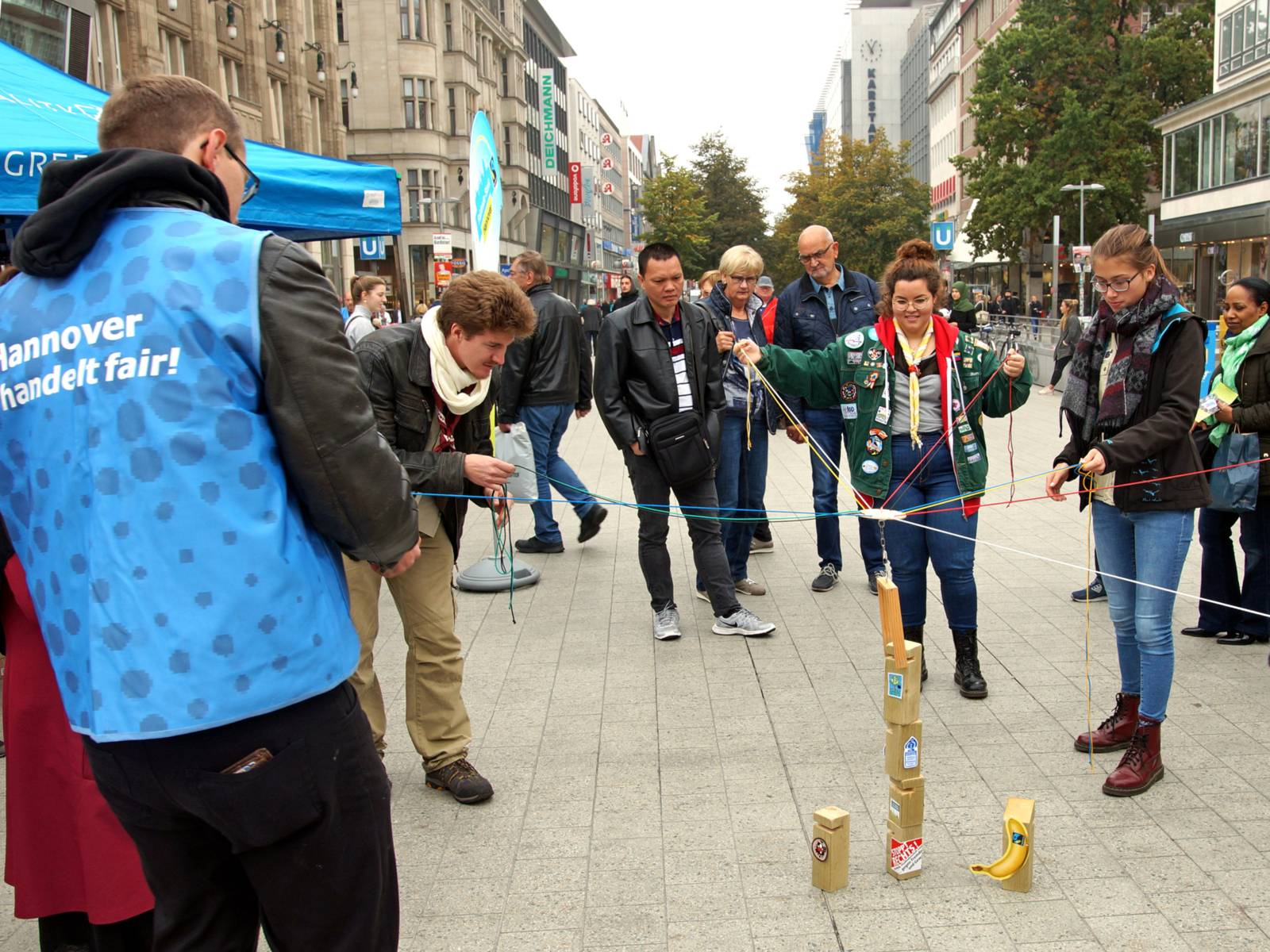 Menschen in einer Fußgängerzone, die junge Leute bei einem Spiel beobachten. 