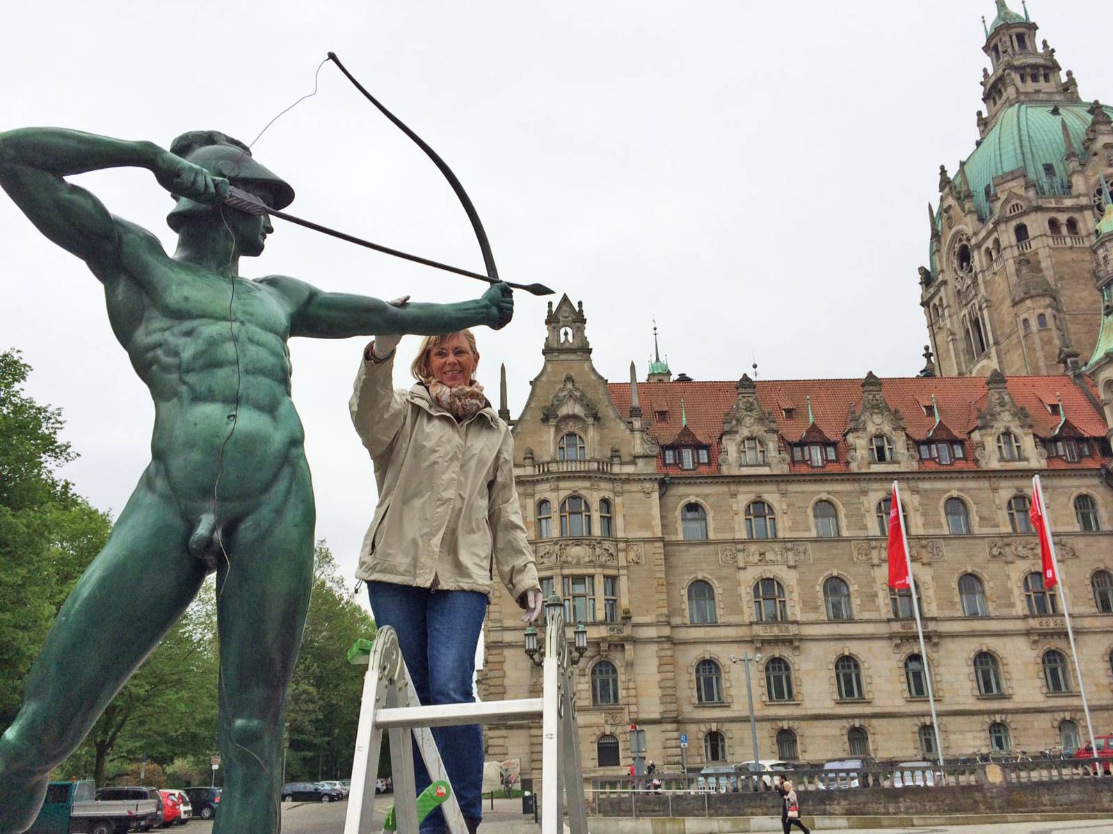 Frau auf einer Leiter, die eine Skulptur berührt. 