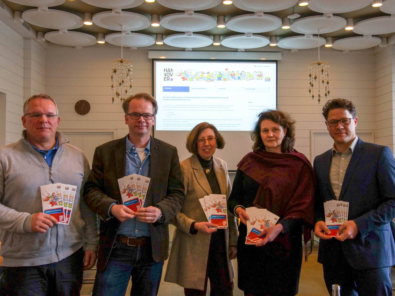 Zwei Frauen und drei Männer mit Broschüren. 