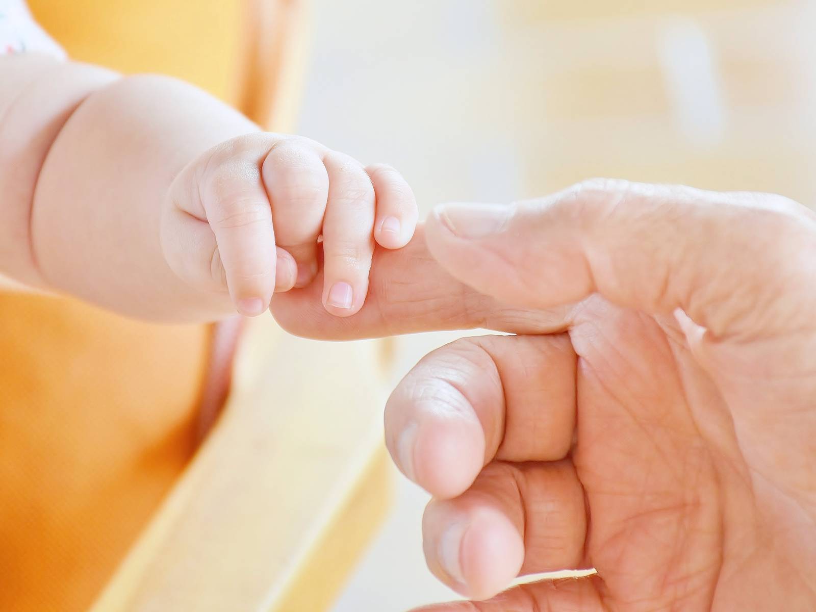 Eine Babyhand greift den Finger eines Erwachsenen