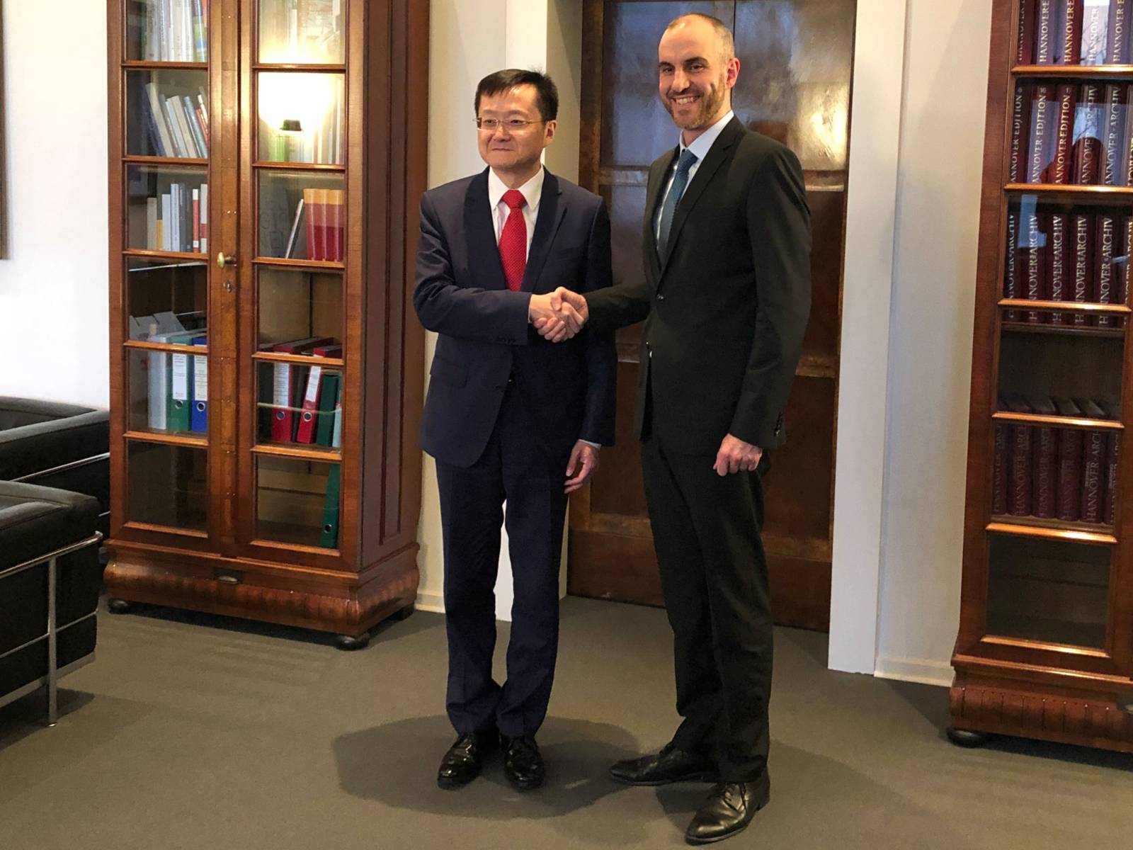 Zwei Männer beim Handschlag in einem Dienstzimmer. 