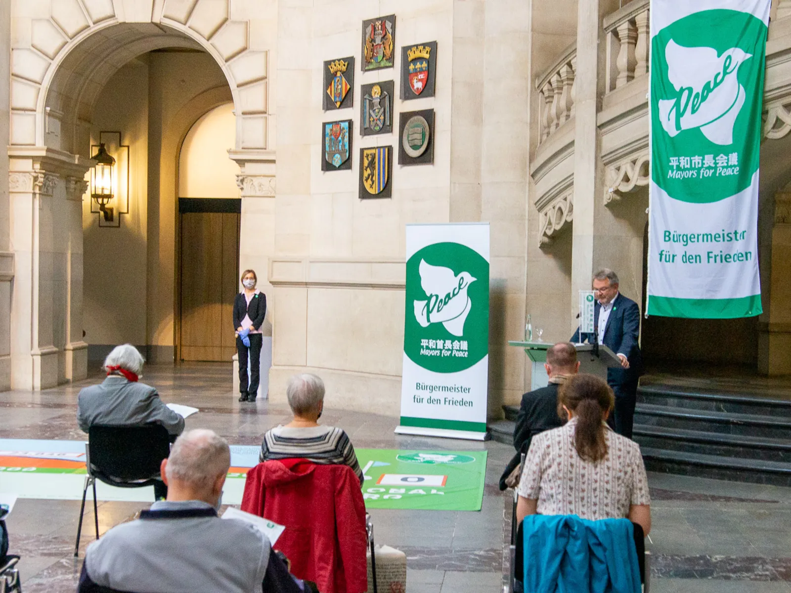 Bürgermeister Thomas Hermann steht an einem Pult in der großen Halle des Neuen Rathauses vor sitzendem Publikum.