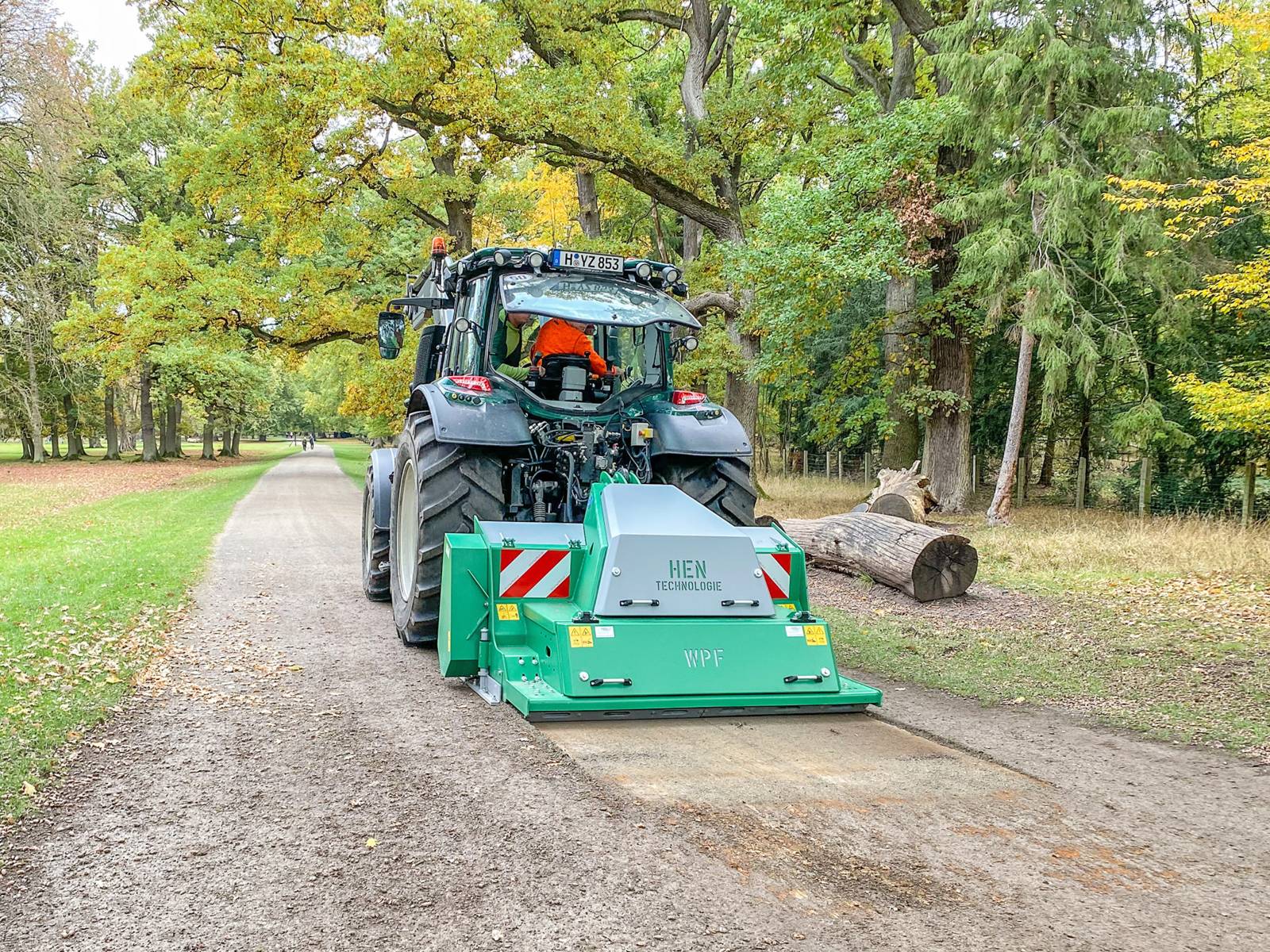 Eine Anbaufräse an einem Traktor, der über einen Weg fährt