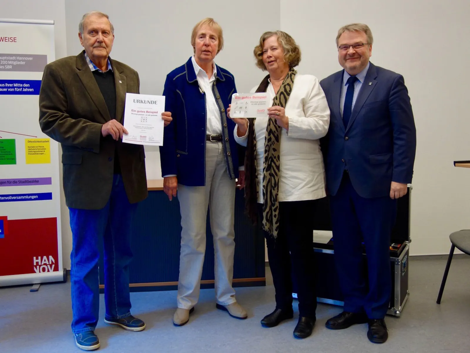 Zwei Frauen und zwei Männer mit einer Plakette.
