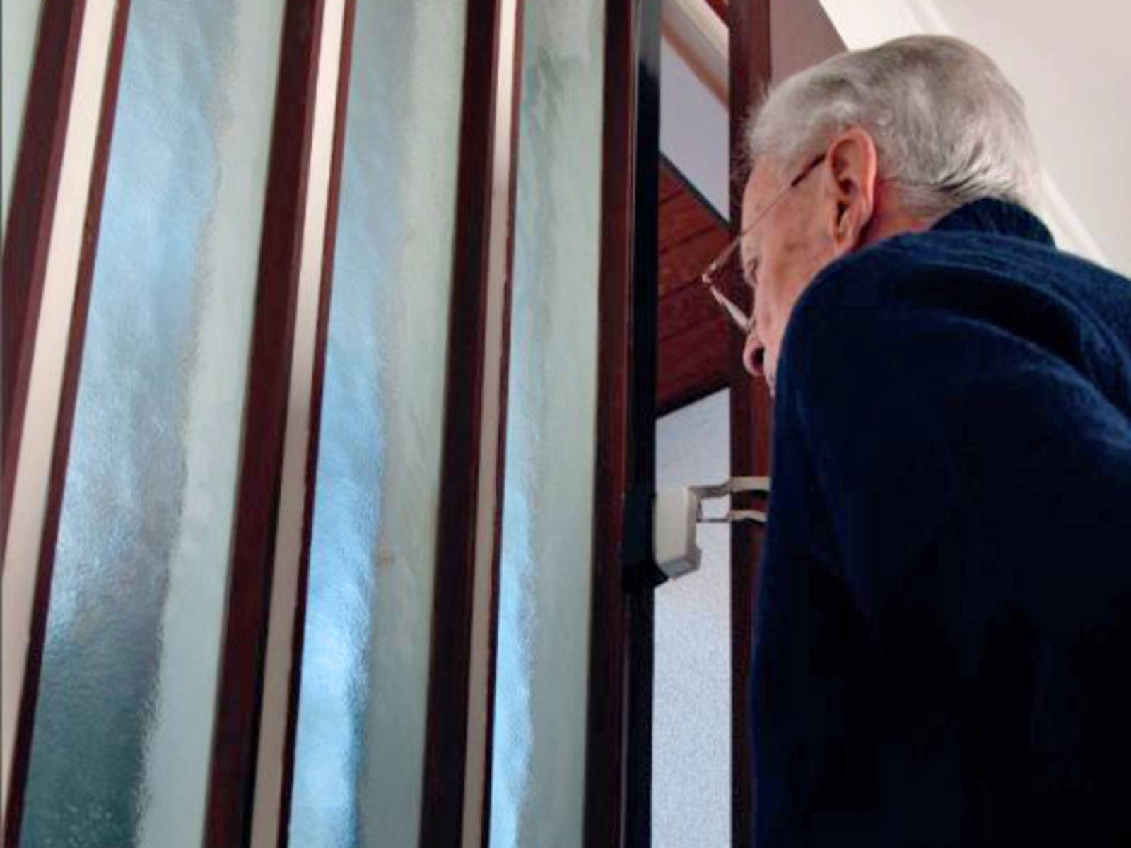 Ein Senior öffnet die Wohnungstür nur einen Spalt weit