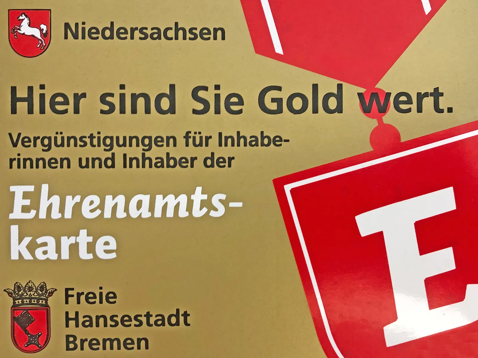 Die goldfarbene Ehrenamtskarte ist so groß wie eine Scheckkarte und trägt die Aufschrift "Hier sind Sie Gold wert - Vergüngstigungen für Inhaberinnen und Inhaber der Ehrenamtskarte".