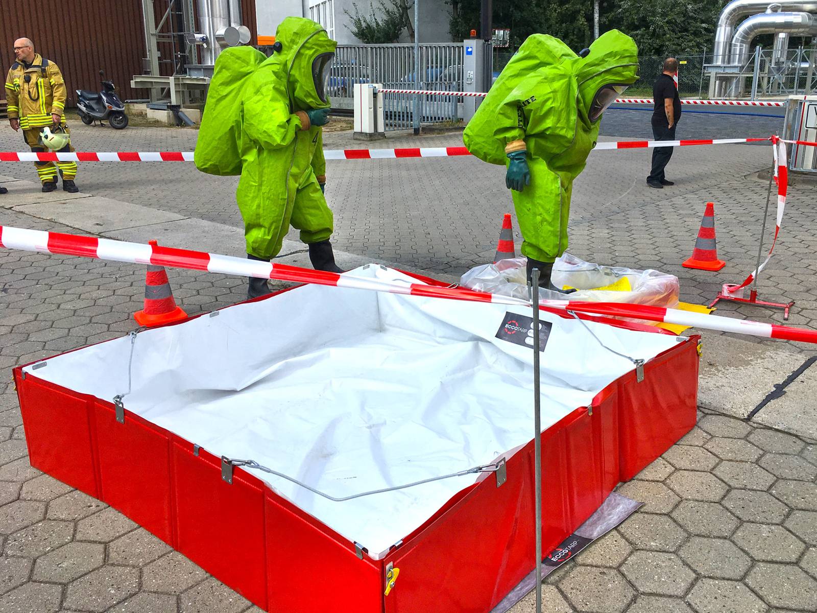 Zwei Einsatzkräfte in Chemikalienschutzanzügen. Im Hintergrund zwei weitere Einsatzkräfte der Feuerwehr Hannover.