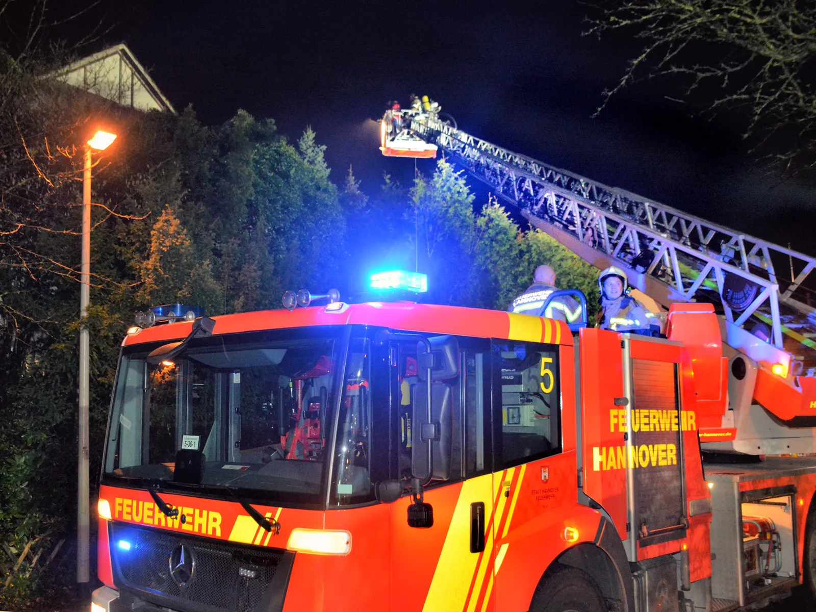 Mehrere Einsatzkräfte der Feuerwehr Hannover bei Löscharbeiten von einer Drehleiter.