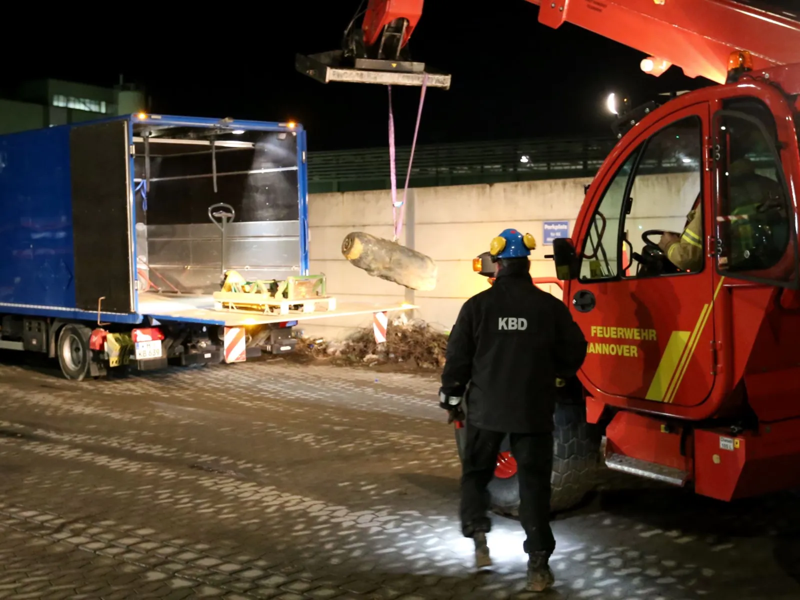 Zwei Männer, die via Kran eine Bombe abtransportieren. 