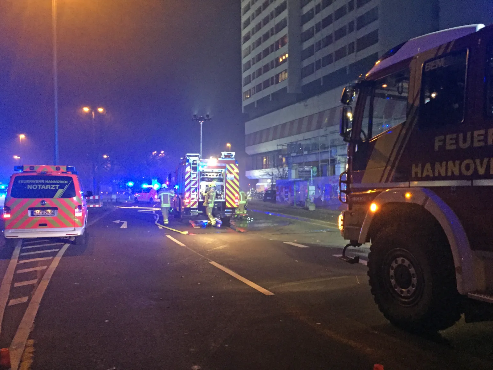 Einsatzfahrzeuge von Feuerwehr und Rettungsdienst vor dem vom Brand betroffenen Wohnhochhaus