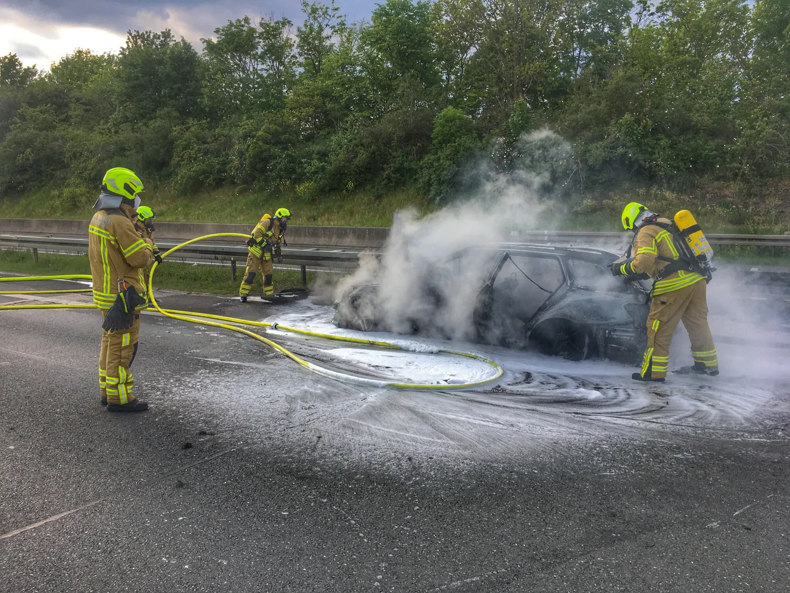 Löscharbeiten an einem Fahrzeugwrack