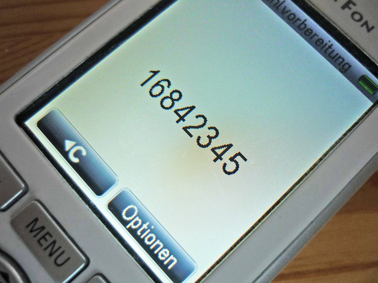 Auf dem Display eines Telefons ist die Nummer 168-42345 zu sehen.