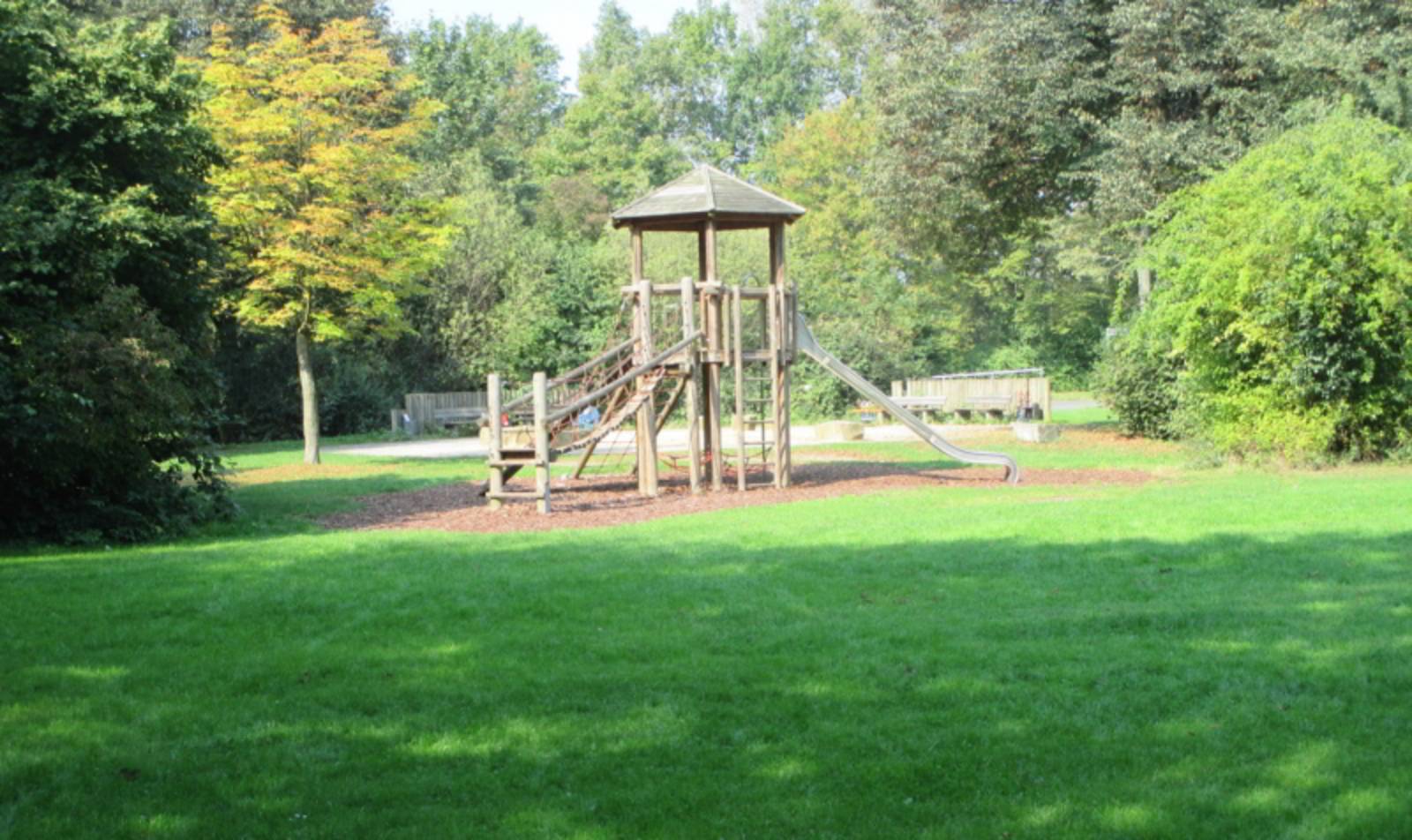 Spielplatz mit großer Rasenfläche und Holzspielgerät
