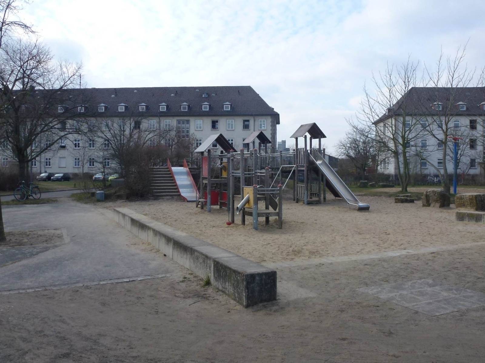 Spielplatz mit großer Sandfläche und Spielgeräten. 