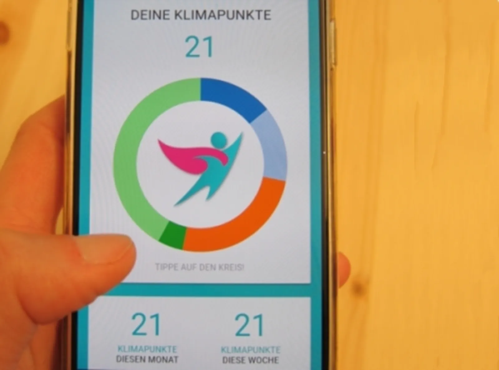 Jemand hält ein Smartphone in der Hand, auf dem die KlimaHelden-App geöffnet ist.