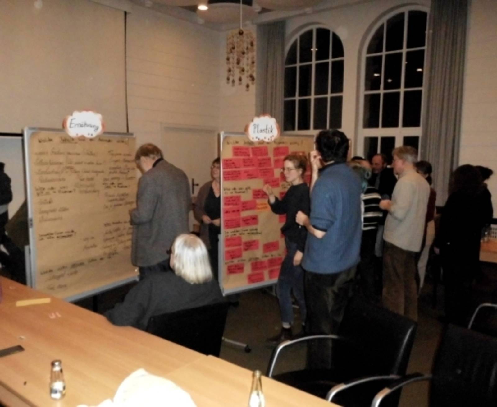 Teilnehmerinnen und Teilnehmer beim Sammeln von Ideen an Moderationswänden.