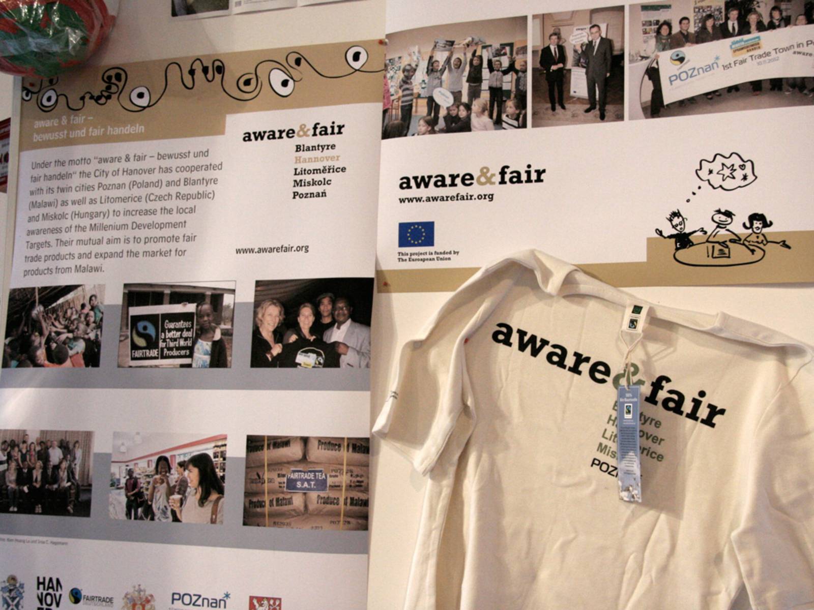 Ausstellungswand, auf der Fotos und ein T-Shirt mit der Aufschrift "Aware & Fair" zu sehen sind