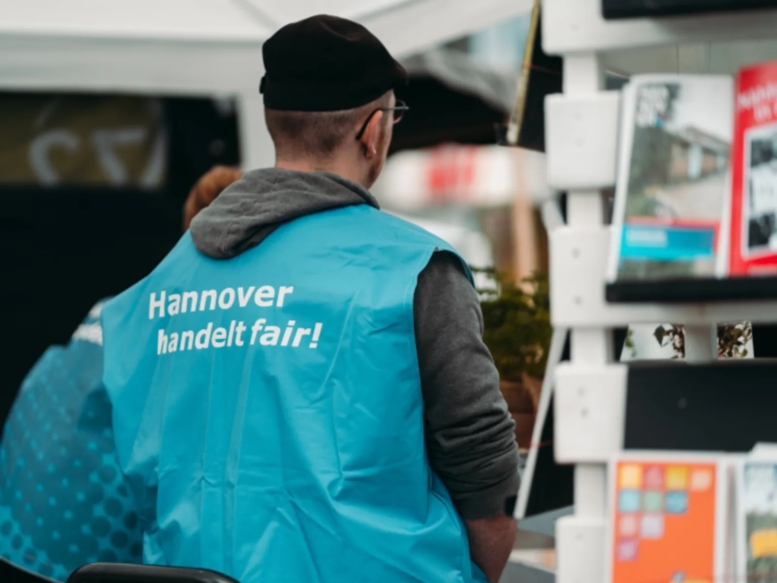 Eine Person von hinten mit Weste und der Aufschrift  "Hannover handelt fair!"