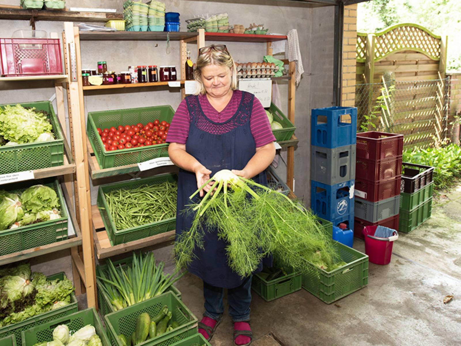 Frau mit Gemüse in einem Hofladen.