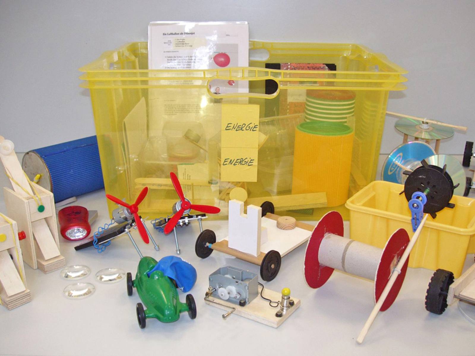 Eine gelbe Plastikkiste mit dem Aufkleber Energie und zahlreiche Miniaturmodelle zum Experimentieren