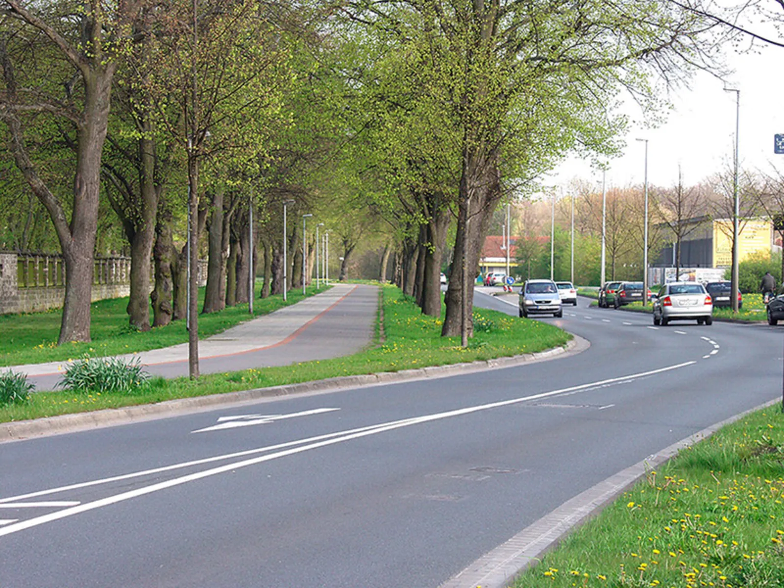 Autos fahren auf einer erneuerten Fahrbahn. Daneben ein sanierter Fahrrad- und Fußgängerweg.