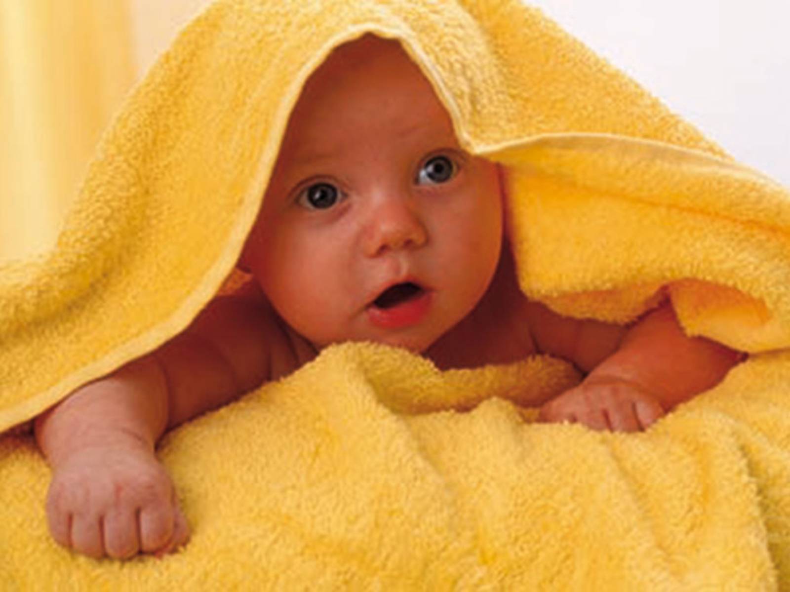 Ein Baby unter einem gelben Handtuch 