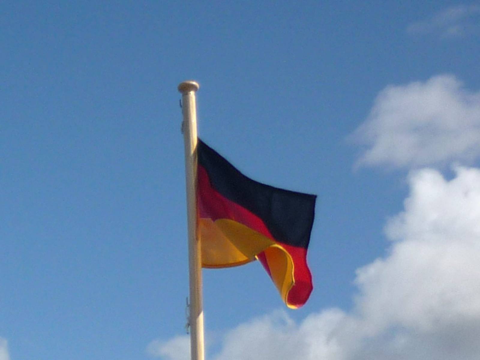 Eine wehende Deutschlandfahne vor blauem Himmel